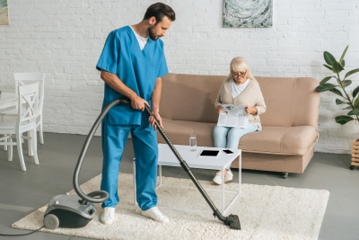 male caregiver cleaning while senior woman is sitting