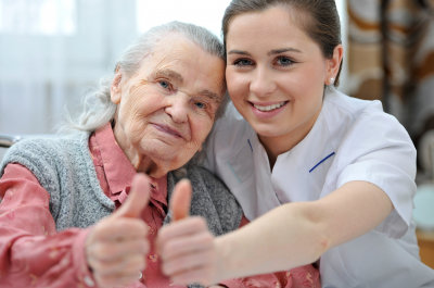 caregiver and senior woman smiling while doing thumbs up