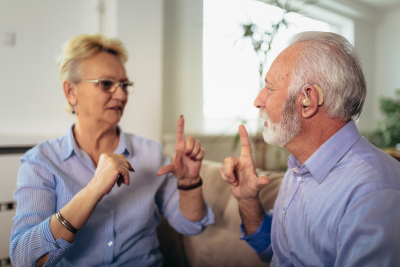 senior wife talking using sign language with her hearing impairment husband