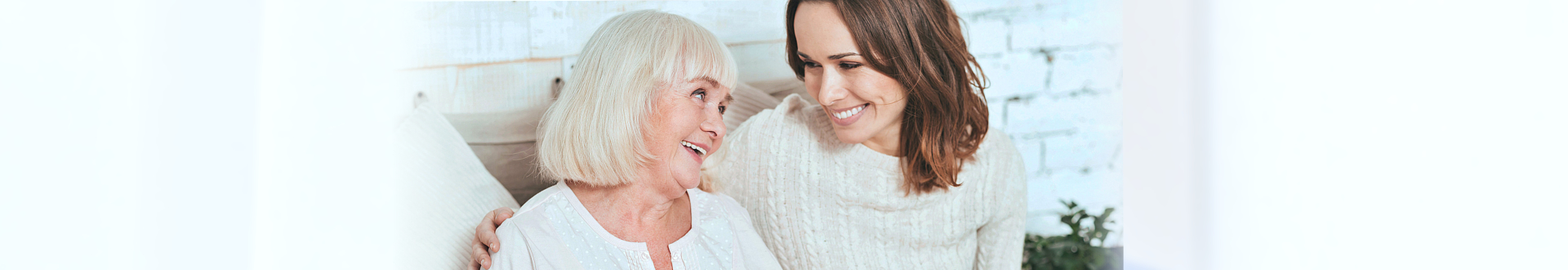 senior woman and caregiver smiling while looking at each other